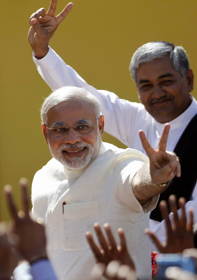 अपने समर्थकों को जीत का इशारा करते मोदी।